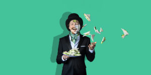 a man in a top hat and tails throwing cucumber sandwiches around